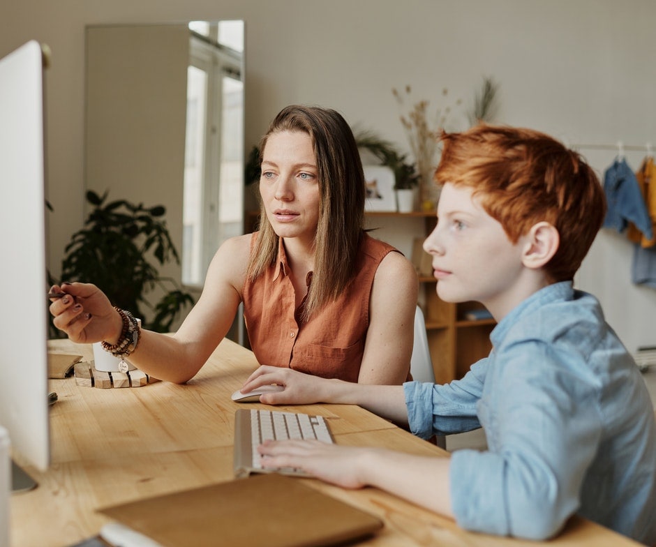 Junge und Frau, die zusammen an einem Computer arbeiten