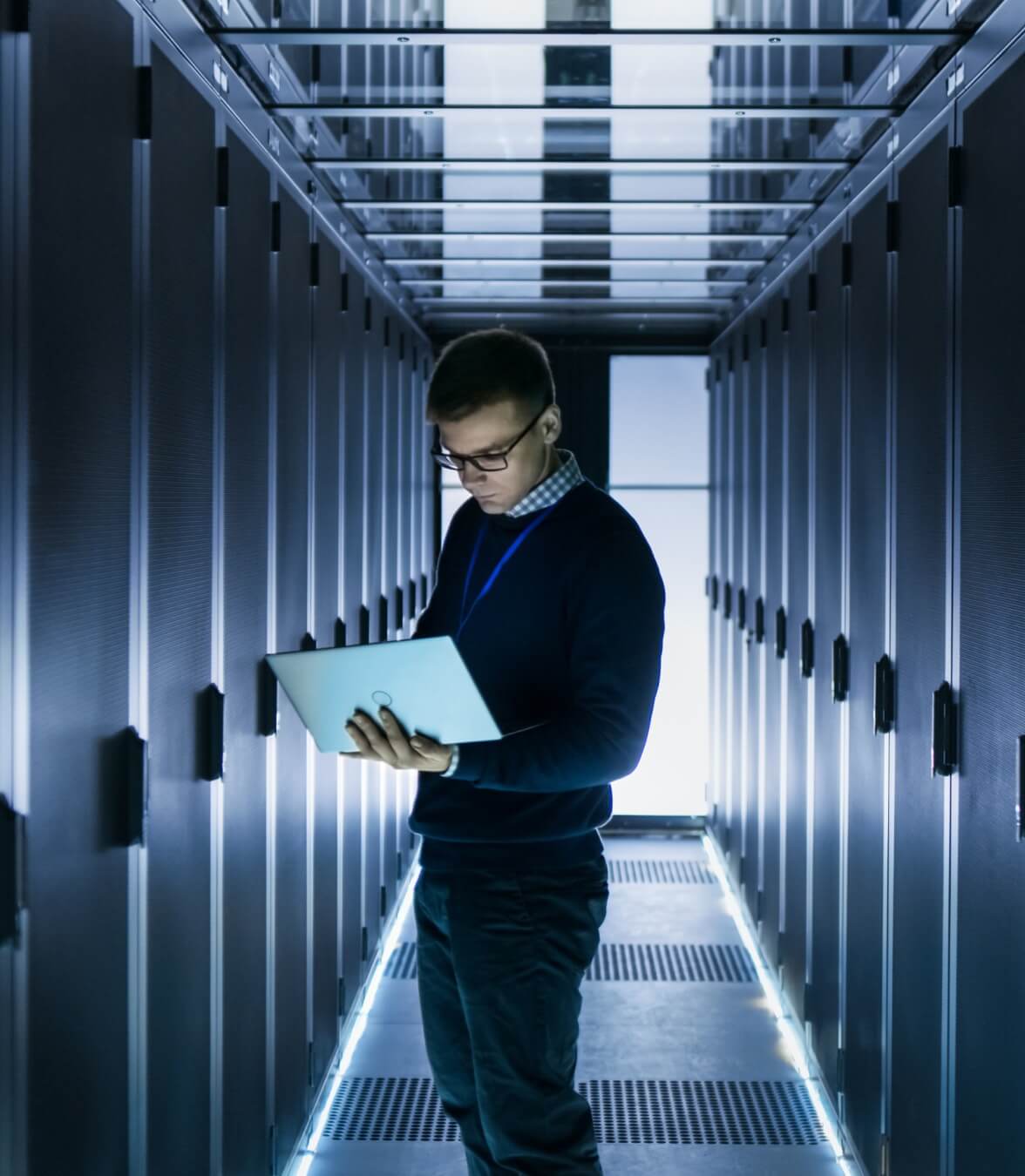 A person standing holding a laptop in hand and working