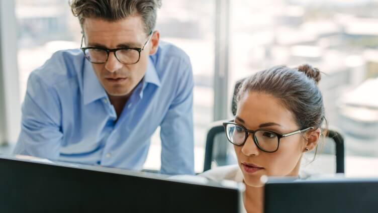 Two people discussing in front of monitor