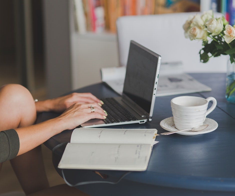 Person working on the laptop with coffee and Notes on the table