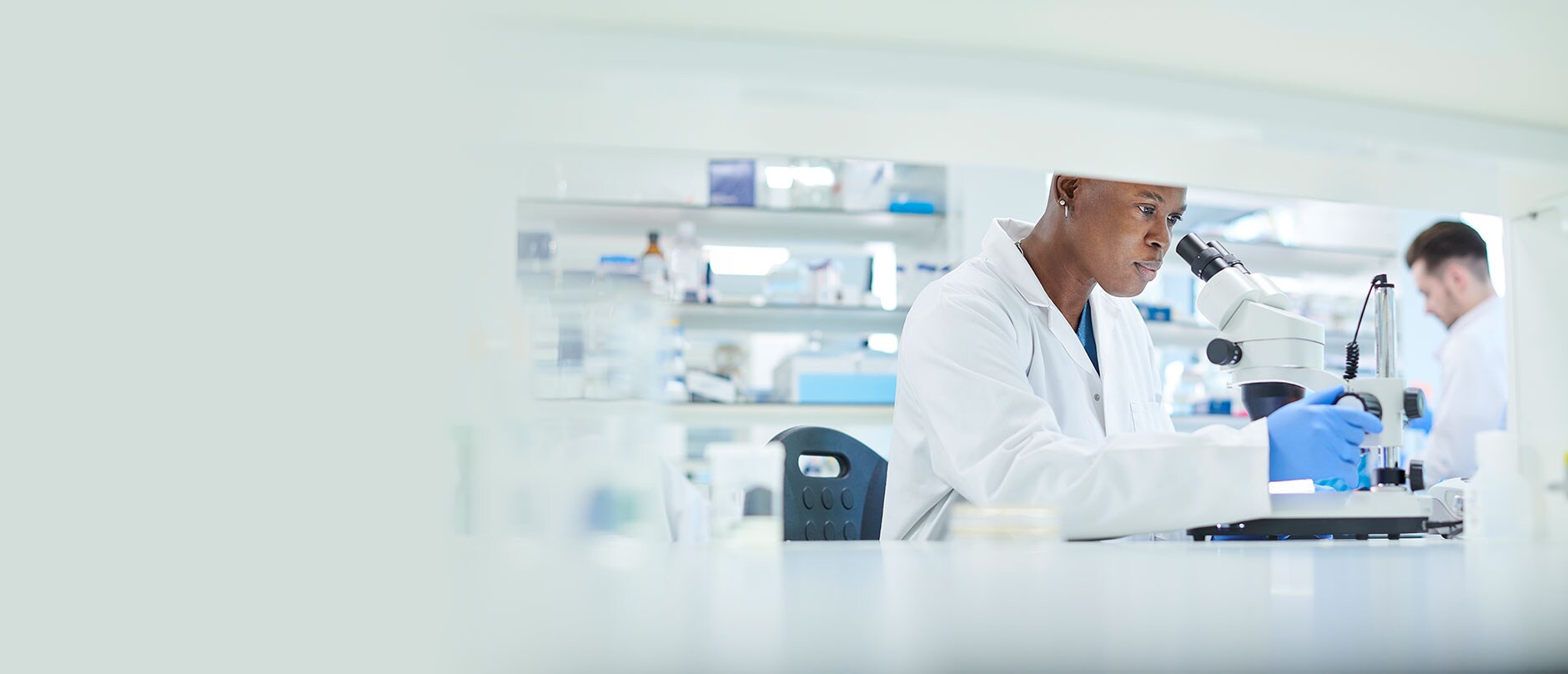 Lab worker looking into microscope 