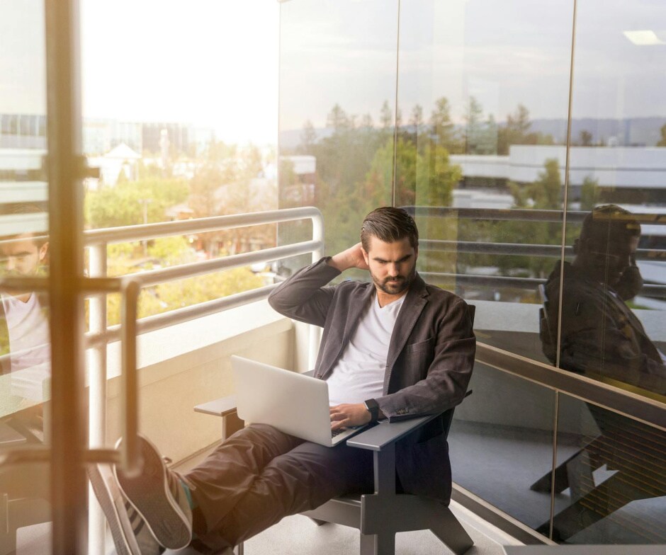 person sitting in office balcony and working on laptop