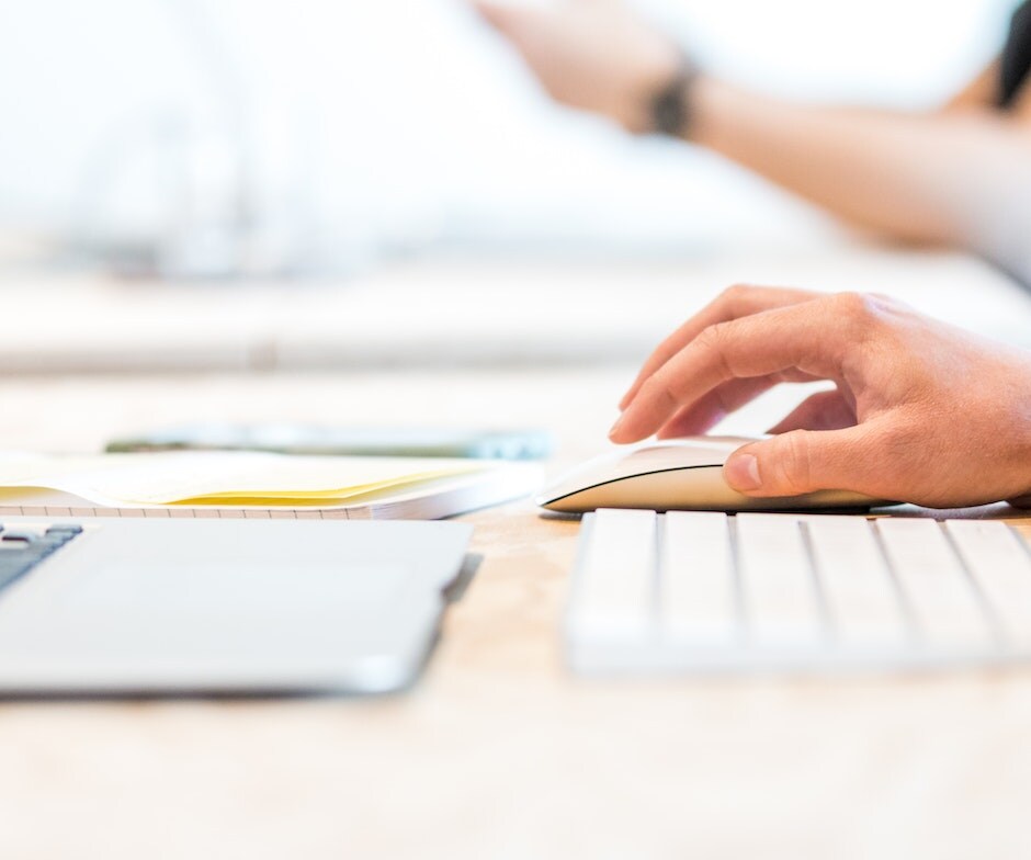 portrait image view of person holding mouse and working in a laptop