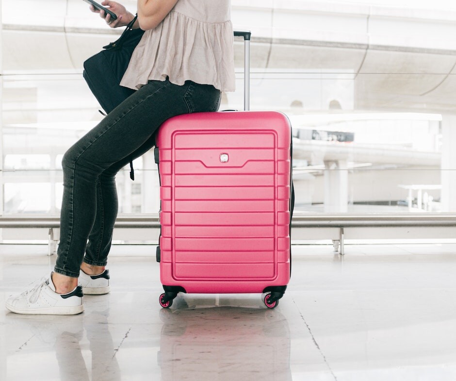 Girl on top of pink suitcase on her phone