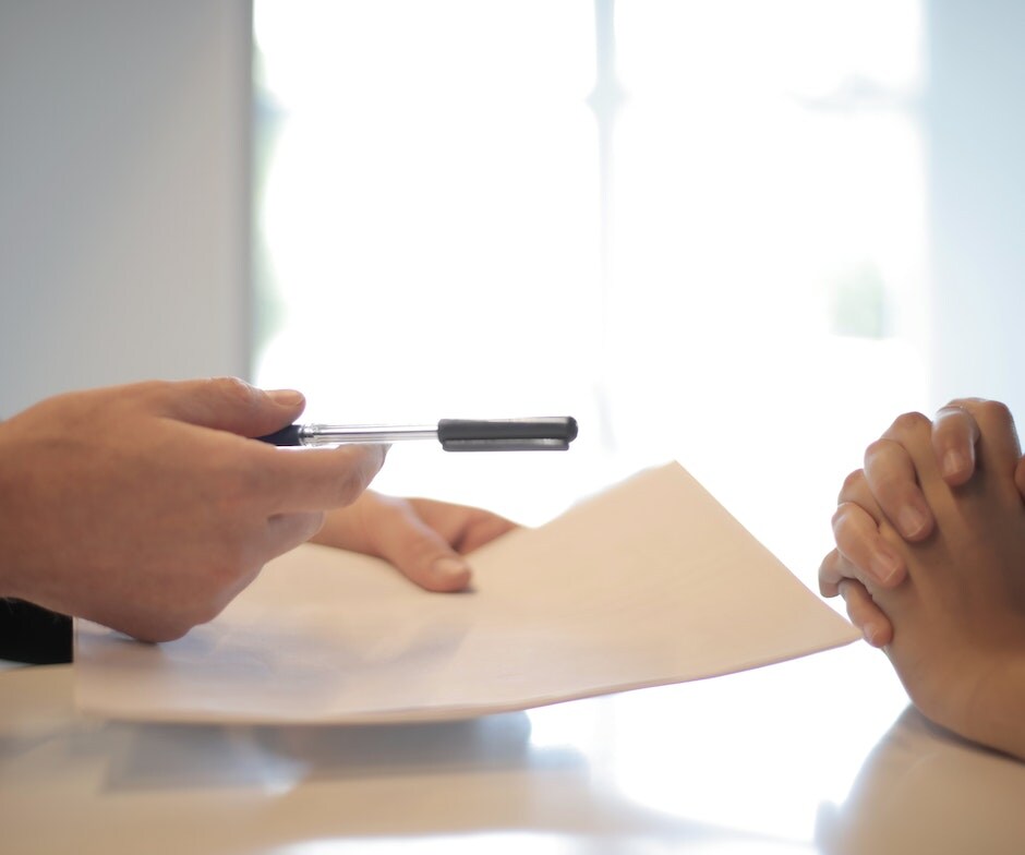 a person handing over a paper to be signed by another person